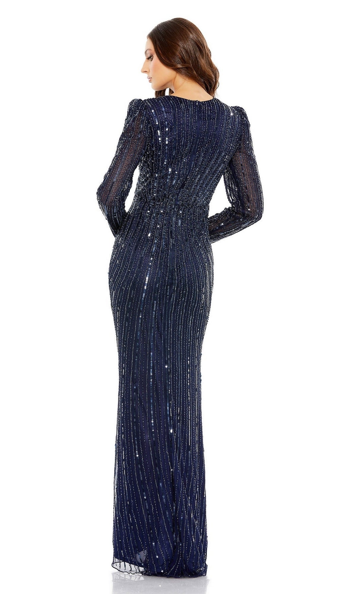 A woman stands with her back to the camera wearing the Mac Duggal 5641 long-sleeve sequin formal dress, a floor-length navy blue gown with elegant detailing.